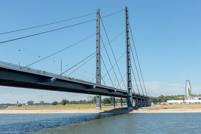 Low angle view of bridge over river against blue sky