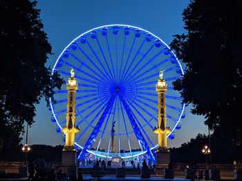 Low angle view of illuminated ferris wheel against sky at night