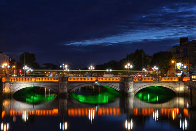 Illuminated bridge over river against sky at night