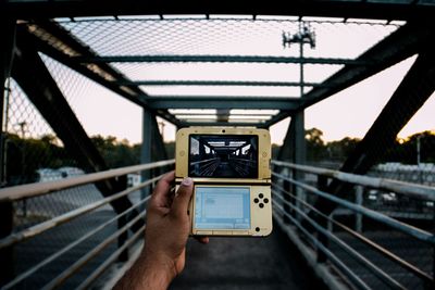 Man photographing through smart phone on bridge