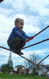 Low angle view of boy balancing on climbing rope at playground