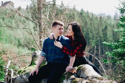 Smiling girlfriend embracing boyfriend in forest