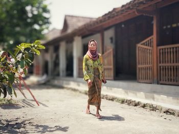 Full length of woman in traditional clothes walking against house