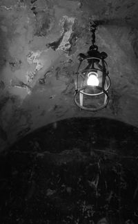 Low angle view of illuminated light bulb hanging on wall