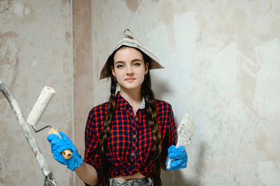 Portrait of young woman standing against wall.  painter works occupation 