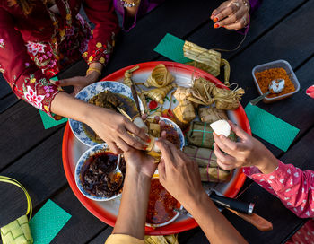 Top view of hands, muslim family, enjoying traditional malay cuisines on tray, at end of ramadan

