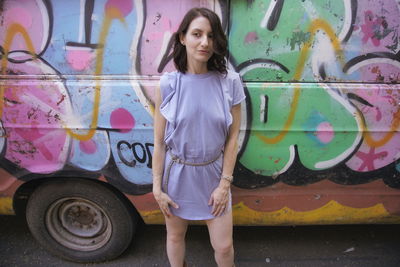 Young woman standing against graffiti on vehicle