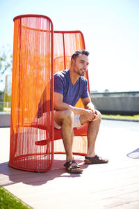 A man sitting outside in a colorful modern chair.
