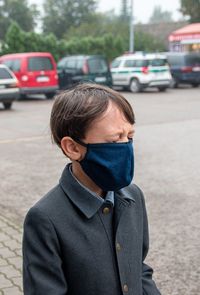 Rear view of boy wearing protection mask, emotionally closed eyes on street in city