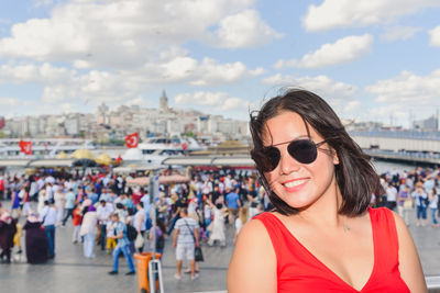 Portrait of smiling woman wearing sunglasses against sky in city