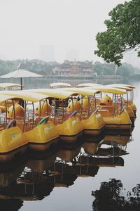 Boats moored by river against sky