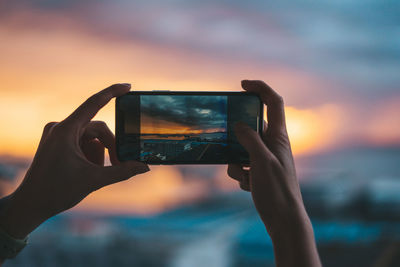 Midsection of person photographing against sky during sunset