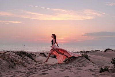 Woman on beach against sky during sunset