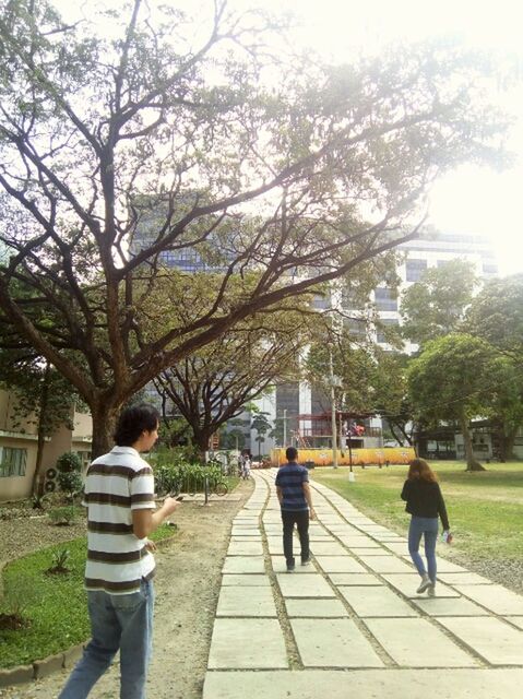 REAR VIEW OF TWO PEOPLE WALKING ON ROAD