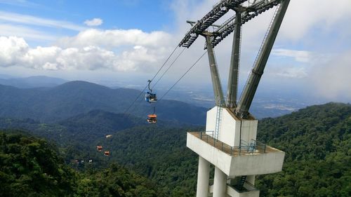 Overhead cable car over mountains against sky