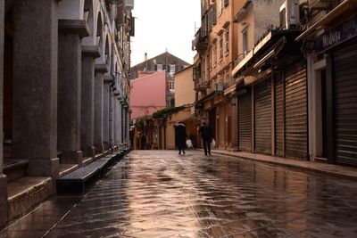 Rear view of woman walking on street amidst buildings