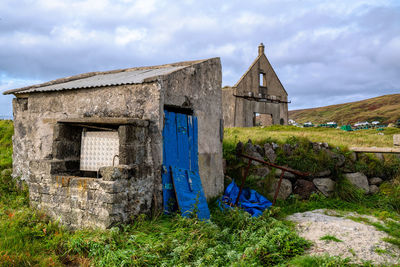 Exterior of old house on field against sky