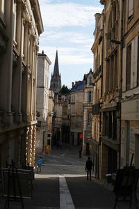 People walking on street in city against sky