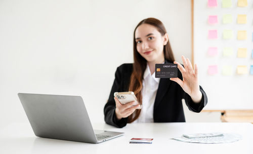 Young woman using mobile phone while sitting on table