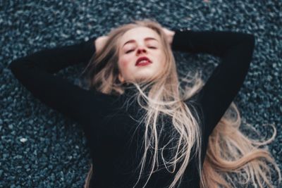 High angle view of beautiful young woman with eyes closed lying on road