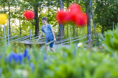 Rear view of boy on plants against trees