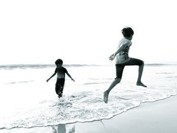 Full length of men on beach against clear sky