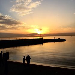 Silhouette of pier in sea at sunset