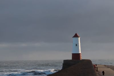 Lighthouse by sea against sky