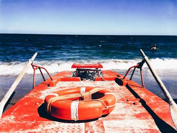 Lifeguard boat on sea shore against clear blue sky