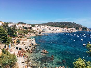 High angle view of town by sea against clear blue sky