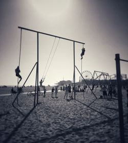 People on swing at beach against clear sky
