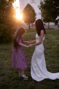 Women standing on field against sky during sunset