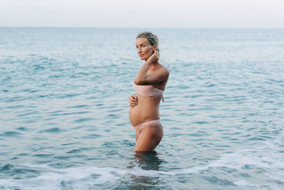 A beautiful pregnant woman enters the sea to freshen up and swim. motherhood and pregnancy.