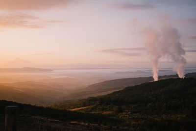 Smoke emitting from chimney against sky at sunset