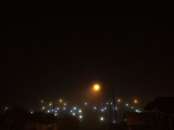 Low angle view of illuminated street lights against sky at night