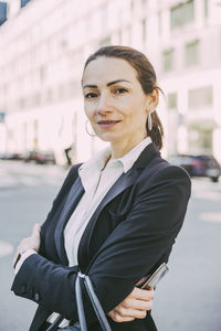 Portrait of confident businesswoman with arms crossed in city