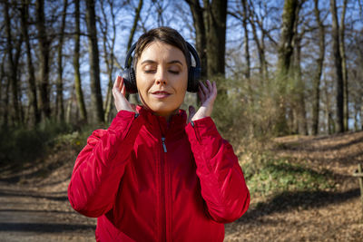 Young woman is training in the forest. woman is listening to the music while she walks in the park.
