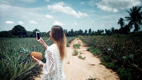 Woman using mobile phone while standing amidst plants