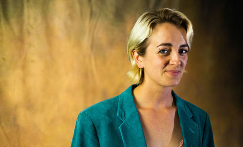 Portrait of young woman standing against wall