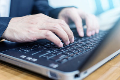 Midsection of man using laptop on table