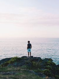 Rear view of man looking at sea against sky
