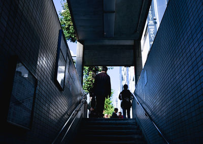 Rear view of people walking on staircase amidst buildings in city