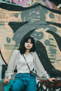 Portrait of beautiful woman against graffiti on wall