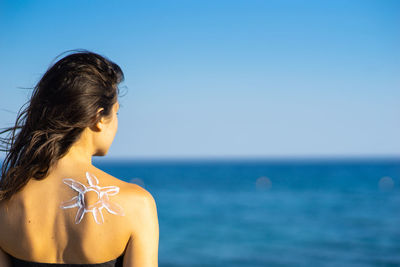 Rear view of woman on beach against sky