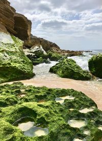 Scenic view of rocks by sea against sky