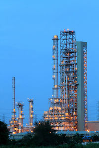 Low angle view of illuminated factory against blue sky