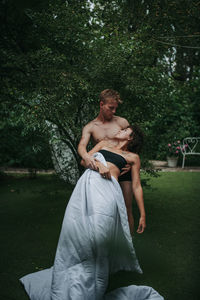 Young couple sitting on grass against trees