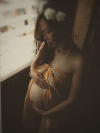 Pregnant woman in bikini standing by window