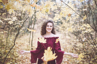 Happy girl in an atumn park throwing maple leaves