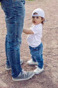 Child in the cap stands next to the parent's father on the sand